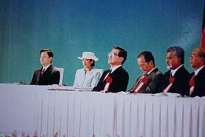 白いテーブルクロスが掛けられた長いテーブルに複数の人物が並んで座り、中央には皇太子御夫妻が座られ、全員が胸に赤いリボンを付けている自然遺産会議の写真