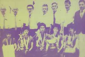 複数の人物が並んで座り、前列の人々は大きな優勝カップやトロフィーを手にし、首にメダルをかけている神山中卓球女子の集合写真