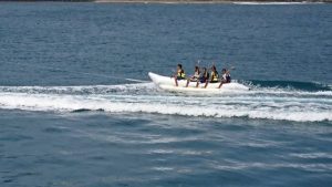 船がたてた白い波の上を複数の人が乗った白いゴムボートが進んでいる様子の写真