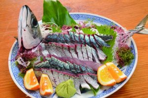 大きな皿に、サバの生き造りが、くし形に切った柑橘類やワサビを添えて盛り付けられた写真