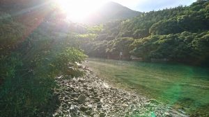 遠景に山が見える、木々に囲まれた美しい川の写真