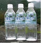 山を背景に、「縄文水」と書かれたラベルがついた透明のボトルが3本並んでいる写真